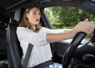 Wanneer is het verplicht om een autogordel te dragen? Lees het hier vrouw geschrokken achter het stuur van een auto